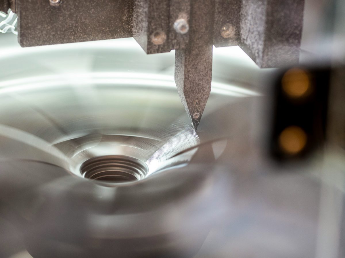 CNC turning tool cutting a threaded bore in an aluminium component, close-up